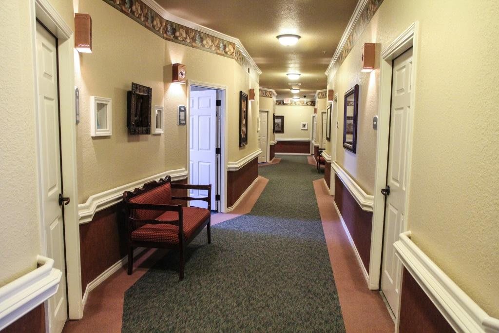 A warmly lit hallway with decorative wallpaper, seating, and multiple doors.