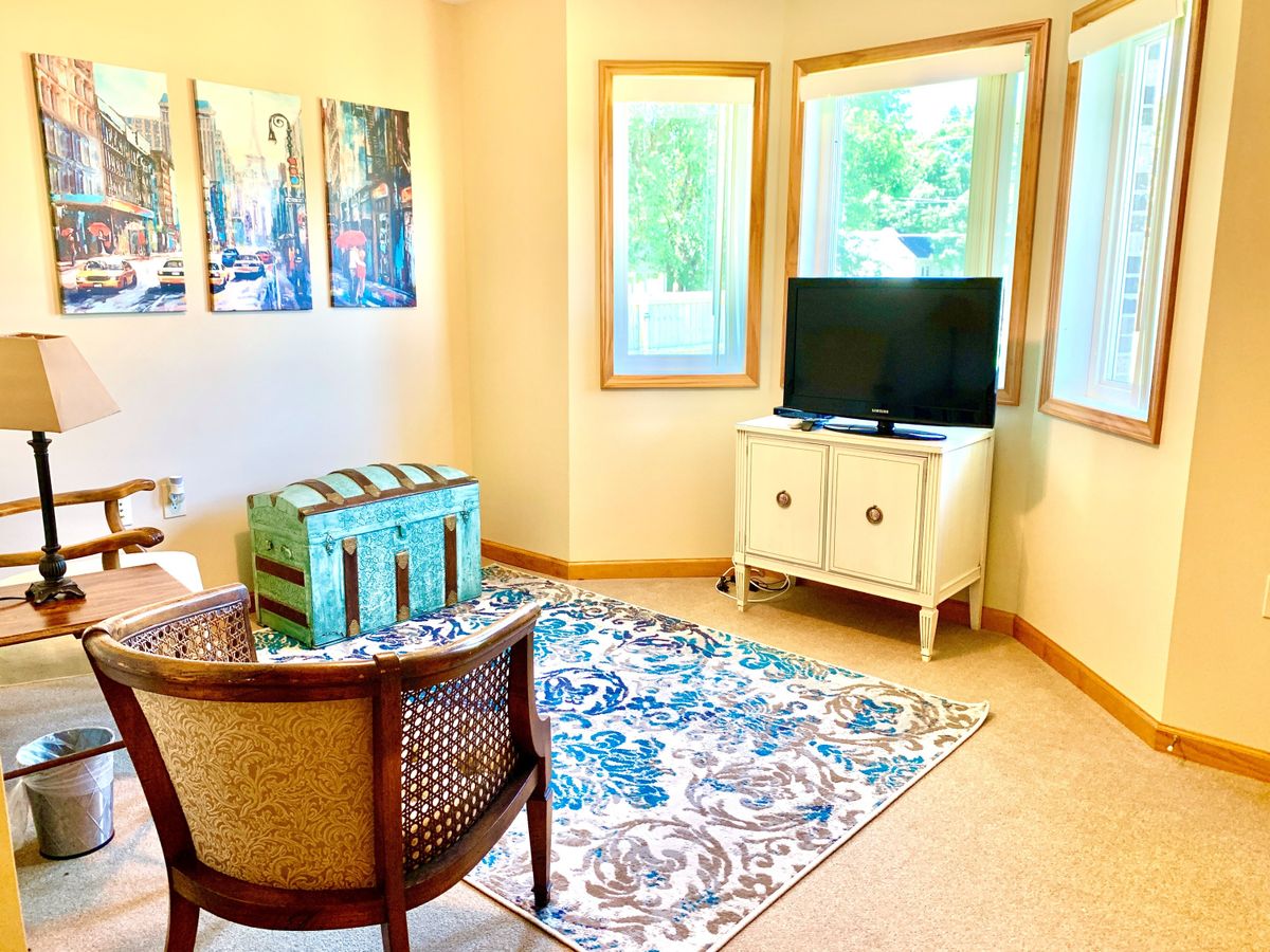 A cozy living room with a TV, artwork on the wall, and a patterned rug.