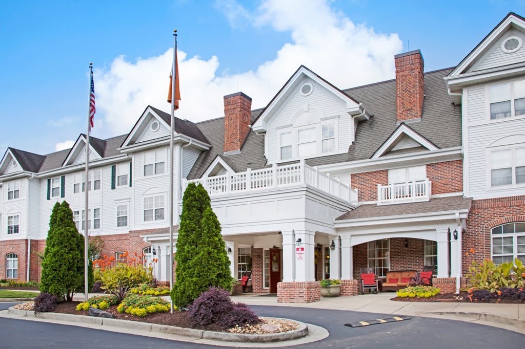 A charming hotel building with a well-landscaped entrance and flags displayed.