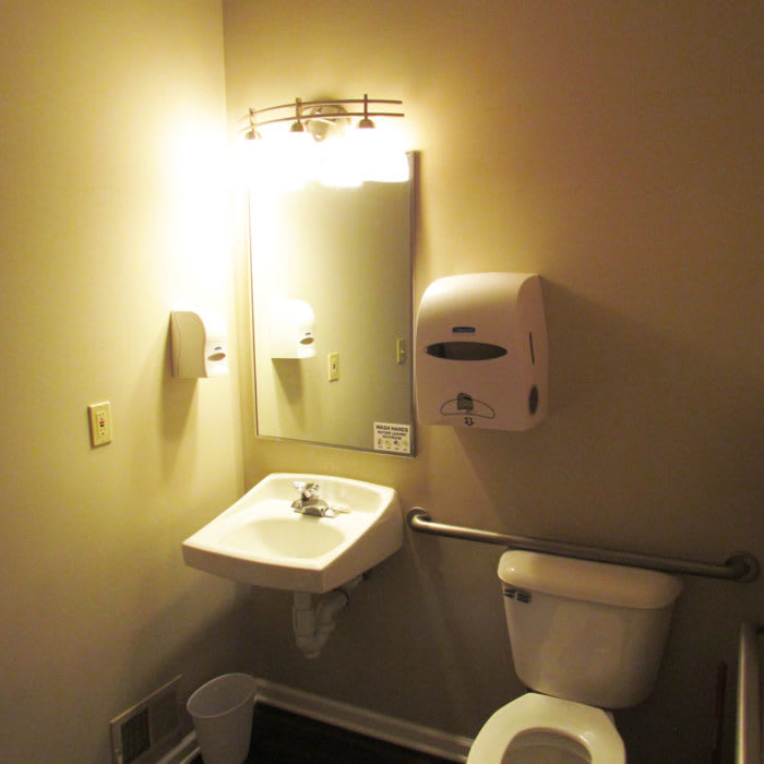 A small, well-lit bathroom with a sink, mirror, and toilet.