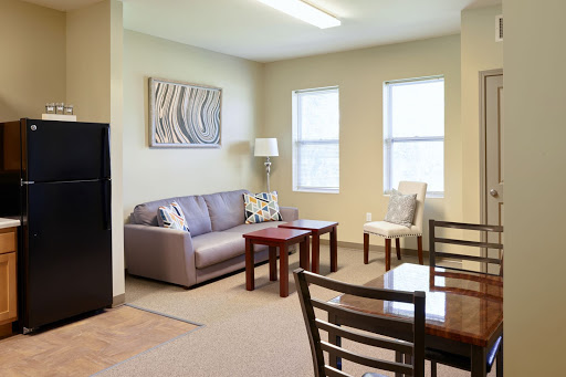 A cozy living room featuring a sofa, table, and natural light from the windows.
