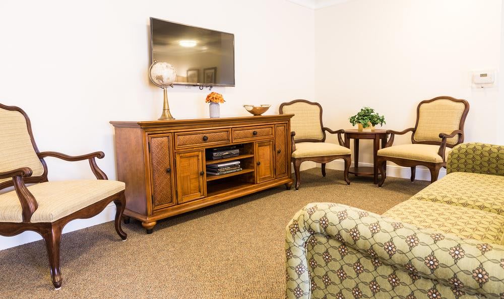 A cozy living room featuring a wooden cabinet with a television mounted above, surrounded by comfortable chairs and decor.