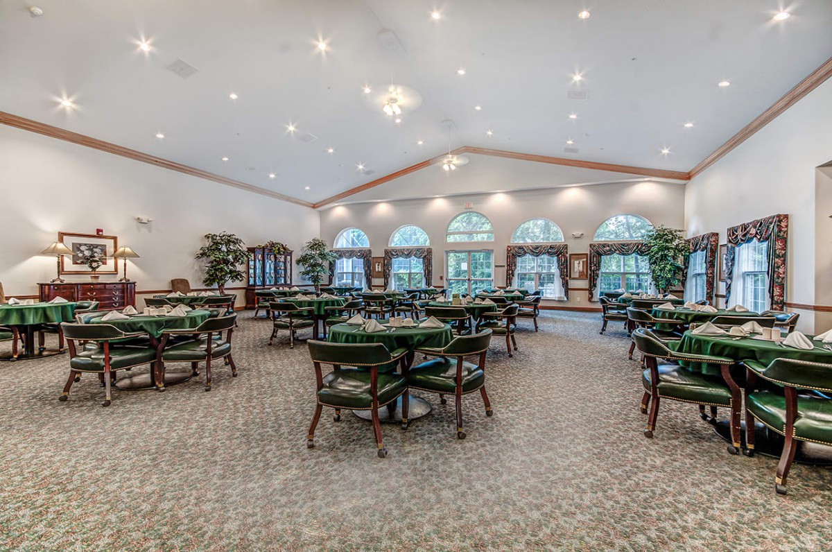 A spacious dining area with multiple tables and chairs, ample lighting, and large windows.