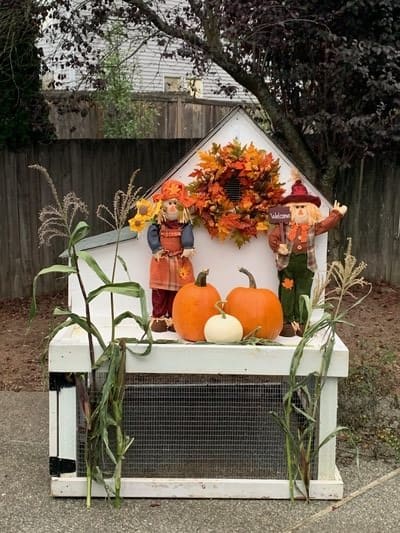 A festive autumn display with pumpkins, scarecrows, and a colorful wreath.