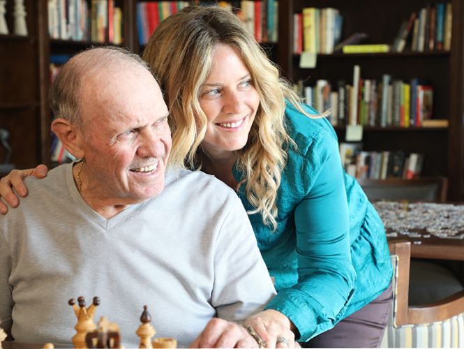 A happy moment shared while playing chess in a cozy library setting.