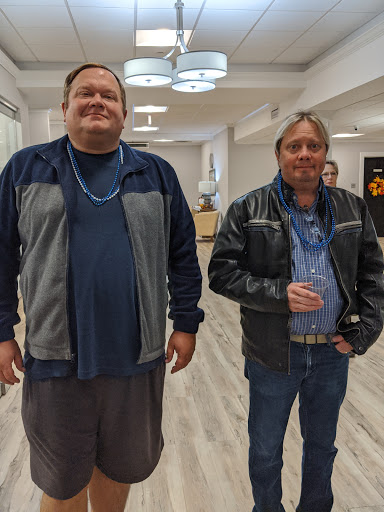 Two men posing together in a modern indoor setting.