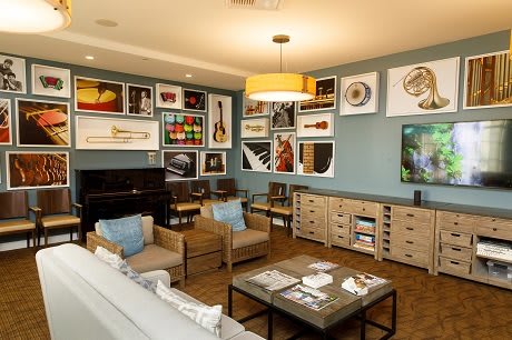 A modern living room with a cozy atmosphere, featuring an art gallery wall and a grand piano.
