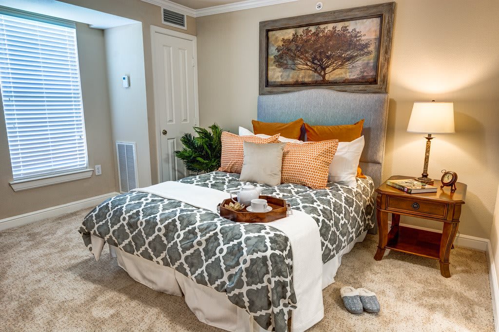 A cozy bedroom with a neatly made bed featuring a decorative tray, pillows, and artwork above the headboard.