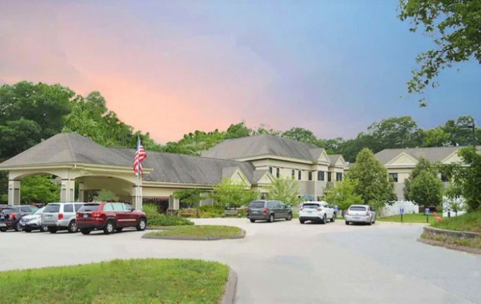A scenic view of a building with a parking lot at sunset.
