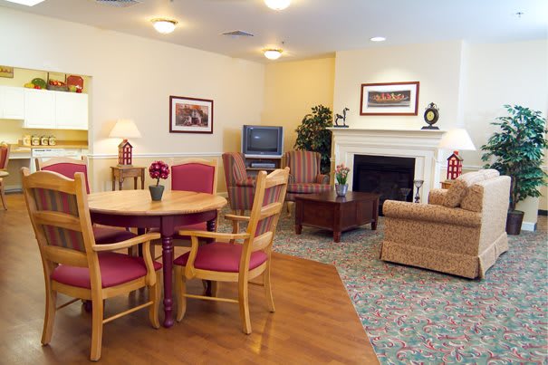 A cozy living room with a round table and chairs, a sofa, a TV, and a fireplace.