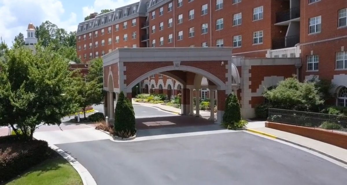 A brick building with an arched entrance and landscaped driveway.