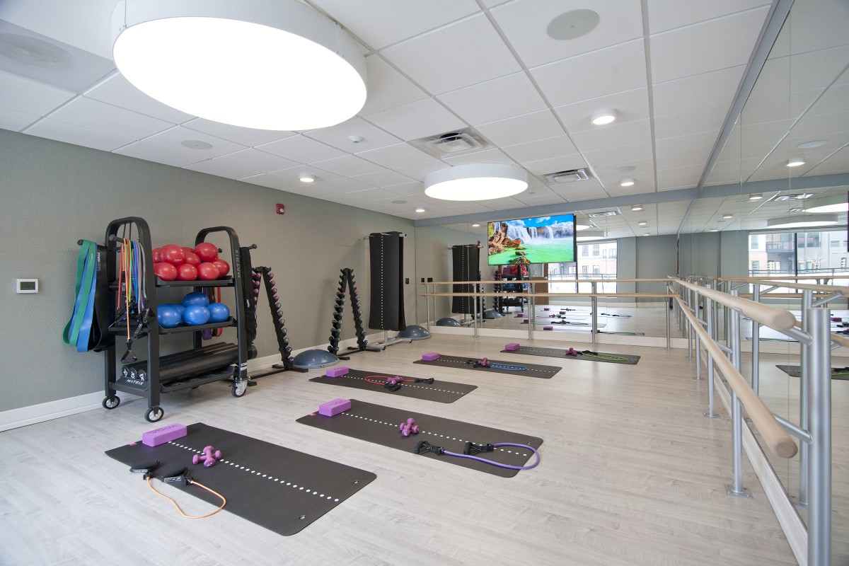 A modern fitness studio equipped with yoga mats, exercise balls, and large mirrors.