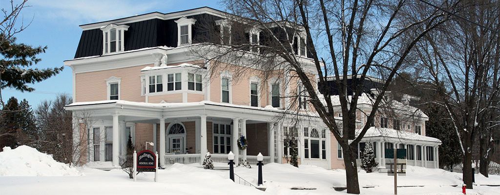 A large house in a snowy winter setting, surrounded by bare trees.