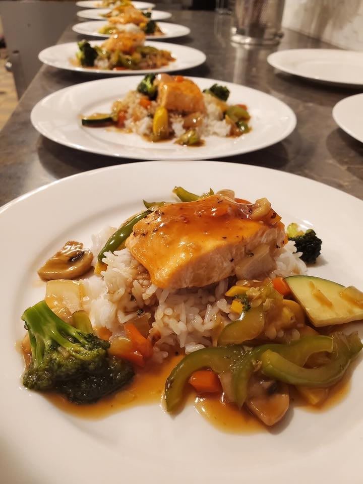 A deliciously plated dish featuring salmon, vegetables, and rice.
