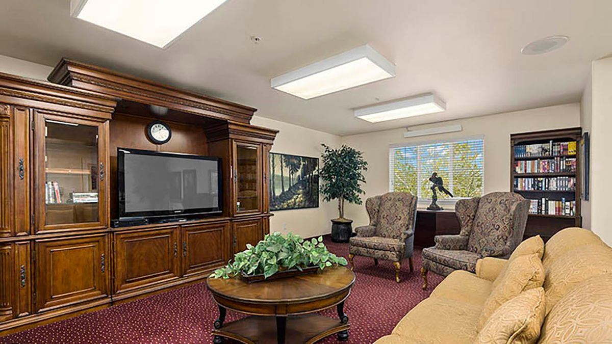 A cozy living room with a large TV, comfortable chairs, and a coffee table adorned with greenery.