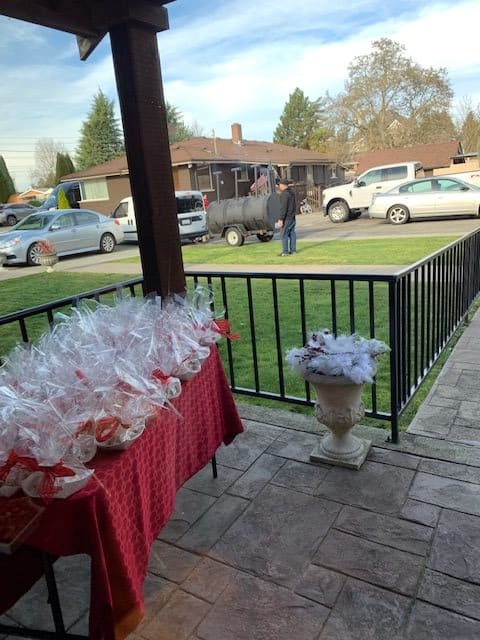 A patio setting with a table covered in wrapped gifts, overlooking a parking area with several cars.