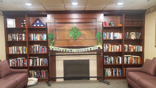 A cozy library setting featuring a display area with green decorations and a banner, surrounded by bookshelves.