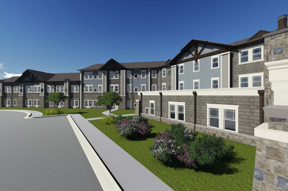 A modern residential apartment building with landscaped surroundings under a clear blue sky.