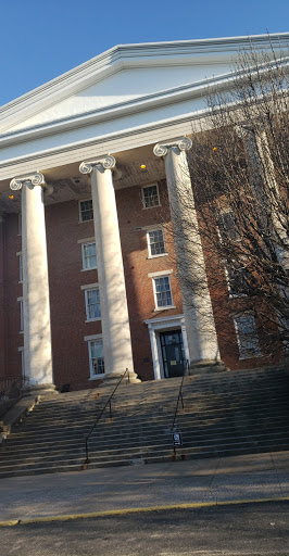 A historic building featuring large columns and a brick facade, complemented by steps leading up to the entrance.