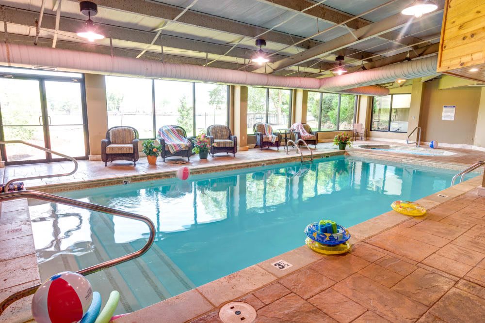 An inviting indoor swimming pool with seating and colorful pool floats.