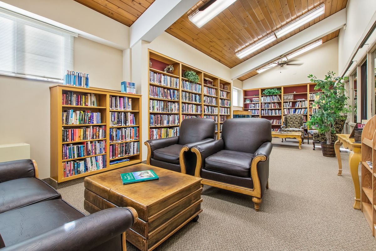 A cozy library reading area with comfortable chairs and bookshelves filled with books.