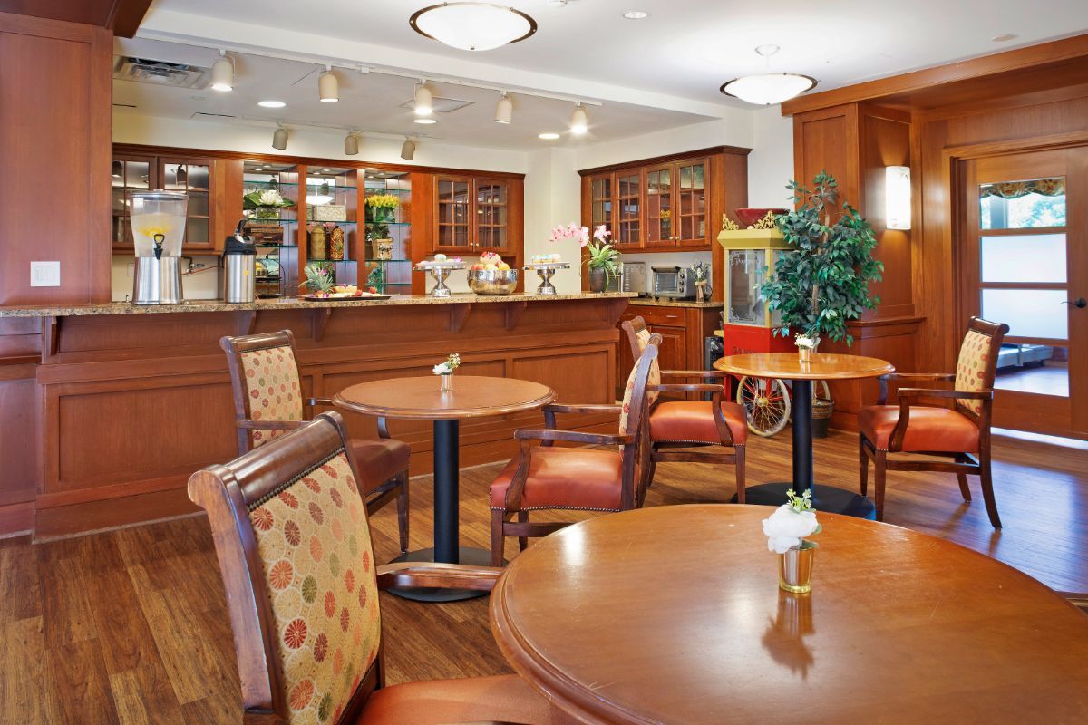 A cozy cafe with wooden tables and chairs, featuring a bar counter in the background.