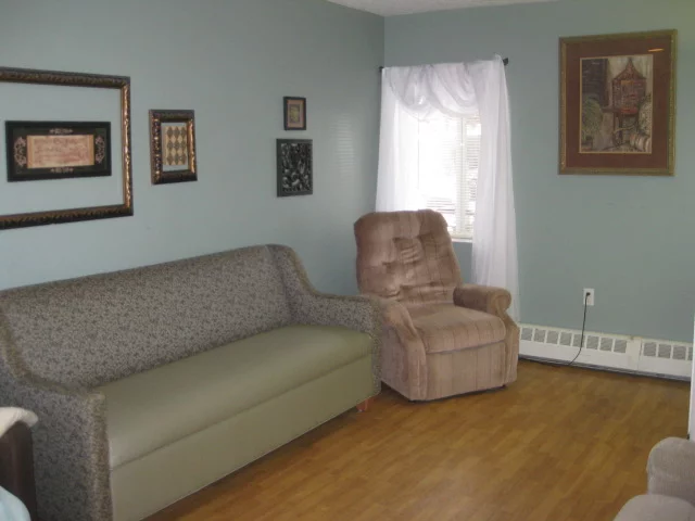 A cozy living room with a sofa, recliner, and decorated walls.