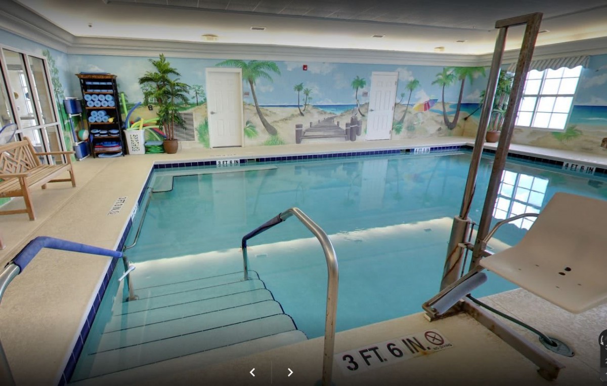 An indoor swimming pool with a beach-themed mural on the wall.