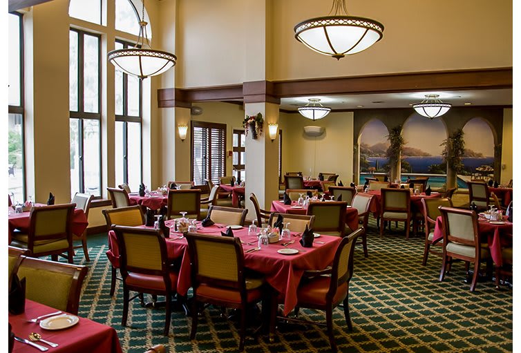 A spacious restaurant dining area with neatly arranged tables and elegant chandeliers.