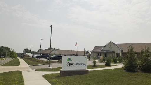 A view of a community center with a prominent sign and an American flag in the background.