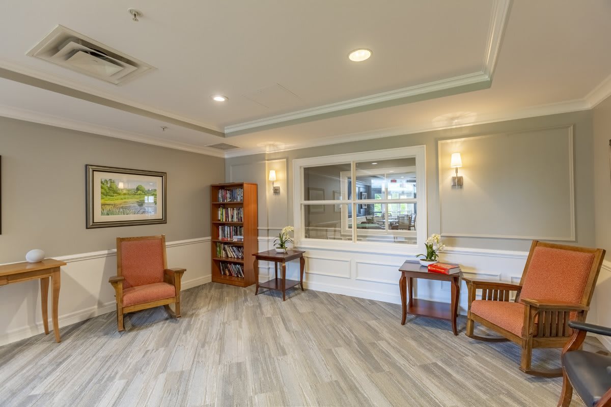 A cozy waiting area featuring comfortable chairs, a bookshelf, and ambient lighting.