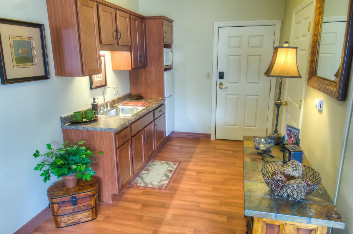 A cozy kitchen area with wooden cabinets, a sink, and decorative plants.
