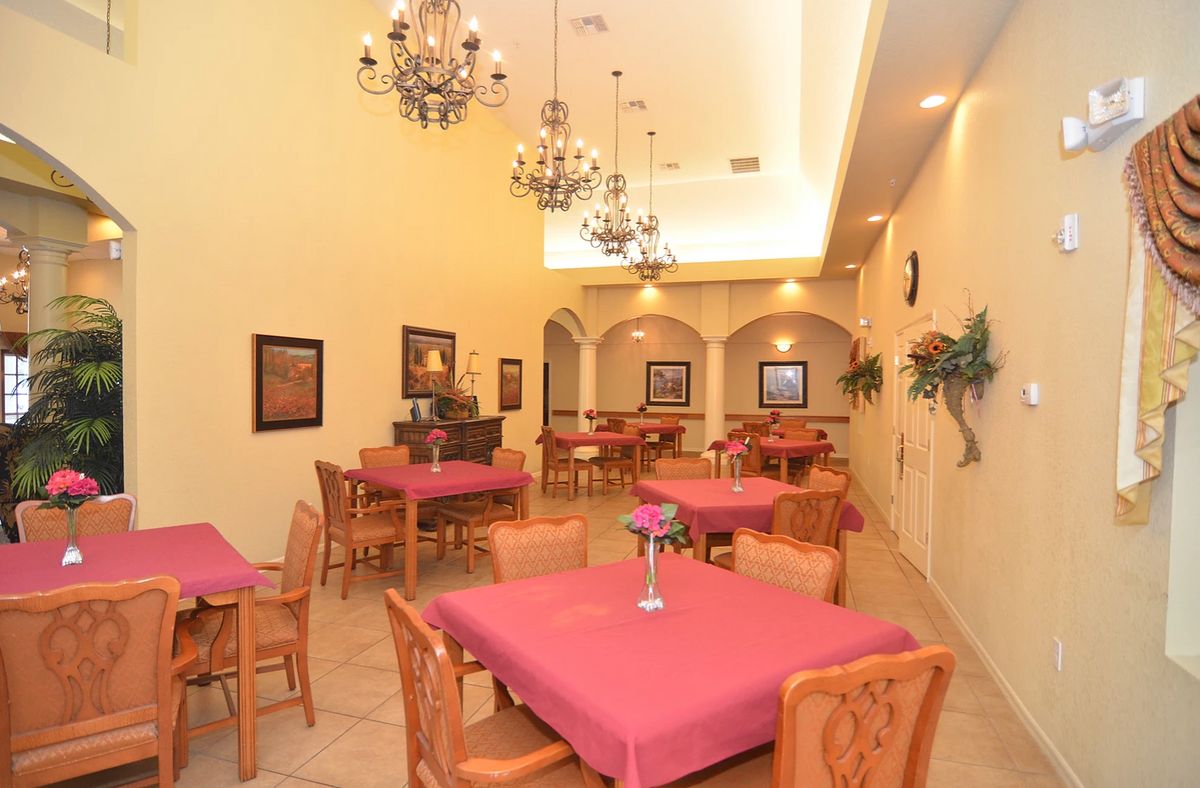 An elegant dining room with chandeliers, decorated with pink tablecloths and wooden furniture.