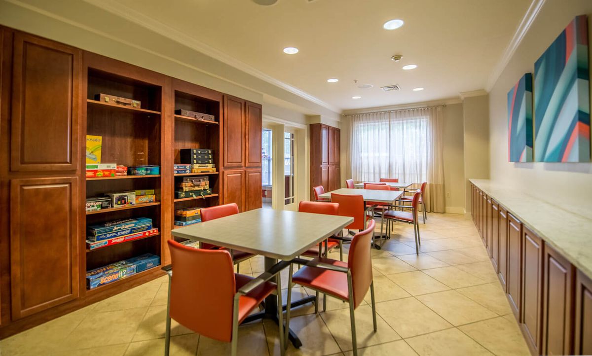 A cozy room with tables and chairs, surrounded by bookshelves stocked with board games.