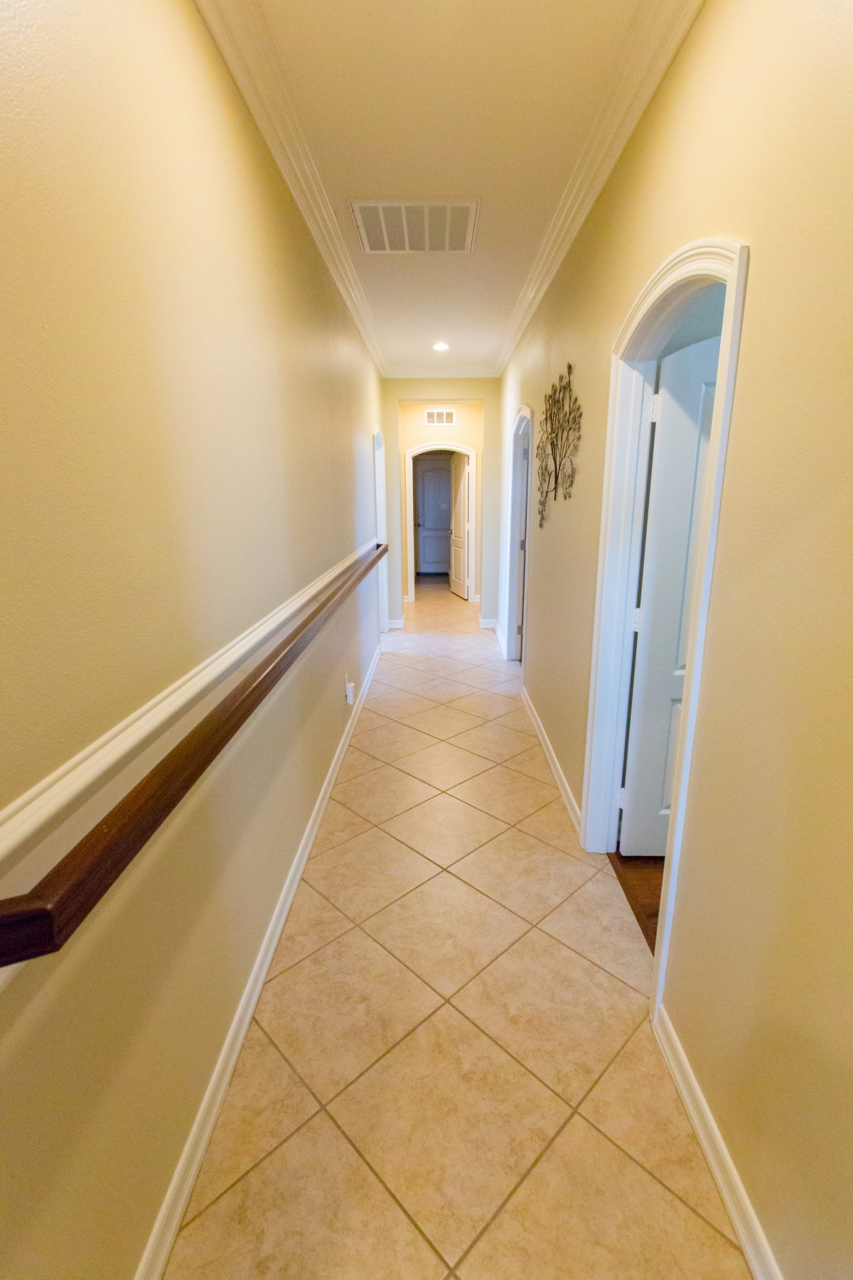 A long, tiled hallway with doors and soft lighting.