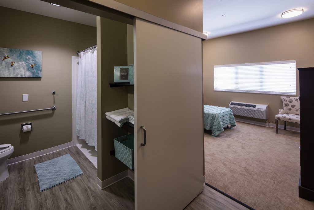A modern interior featuring a bedroom and an adjacent bathroom with a sliding door.