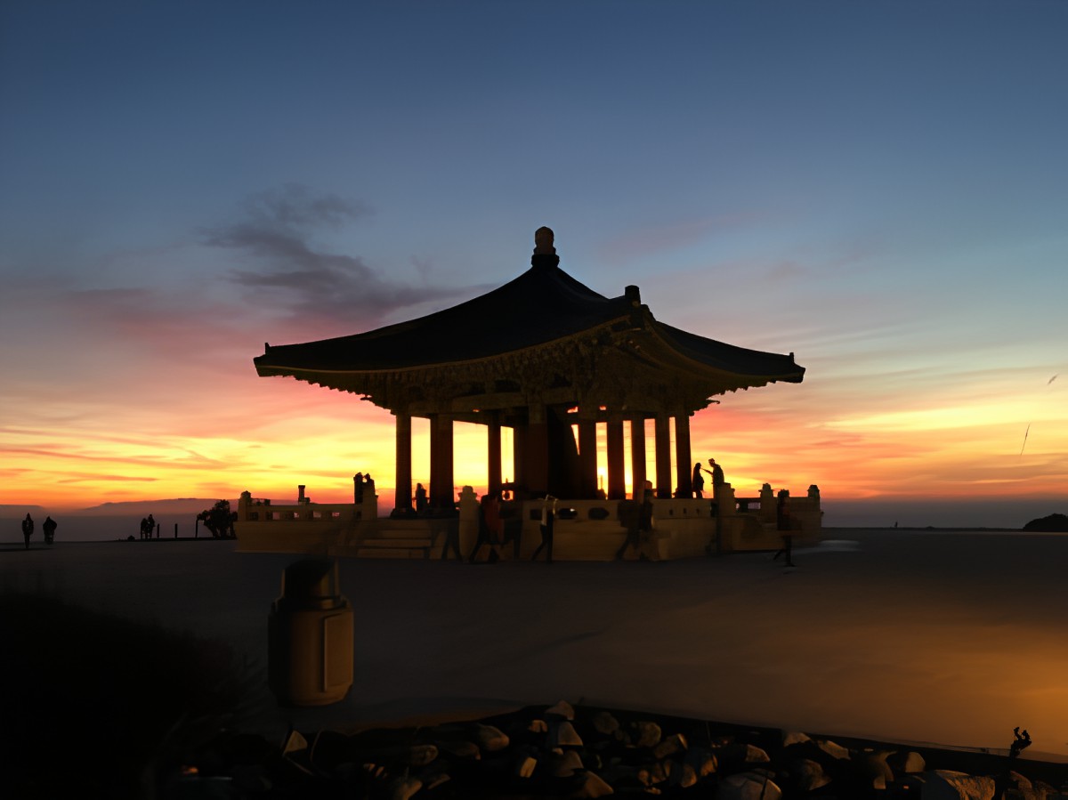 A silhouetted pavilion set against a vibrant sunset sky.