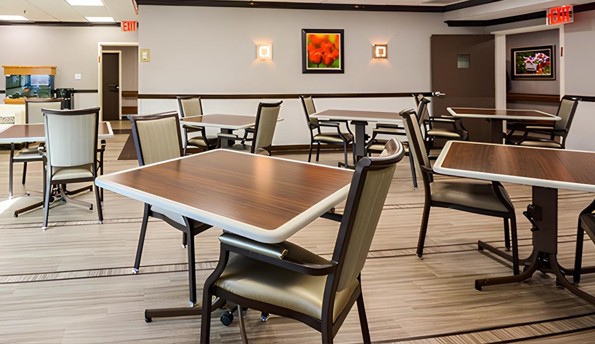An empty dining area with neatly arranged tables and chairs, featuring artwork on the wall.