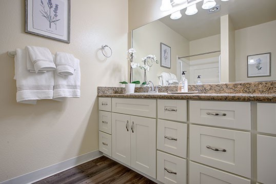 A modern bathroom with a large mirror, a sink, and ample cabinet space.