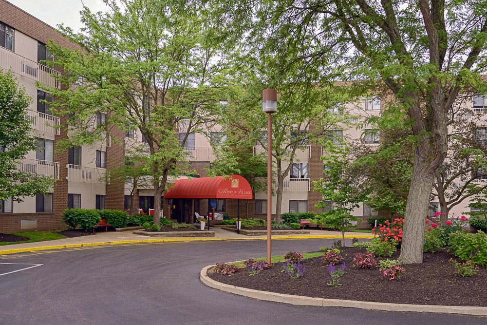 Entrance to an apartment complex with trees and landscaped driveway.