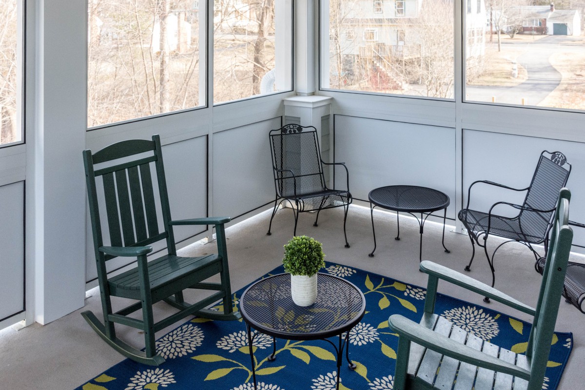 A cozy porch area with a rocking chair, small table, and decorative rug.
