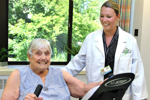 An elderly woman engaging in a fitness activity with the support of a healthcare professional.