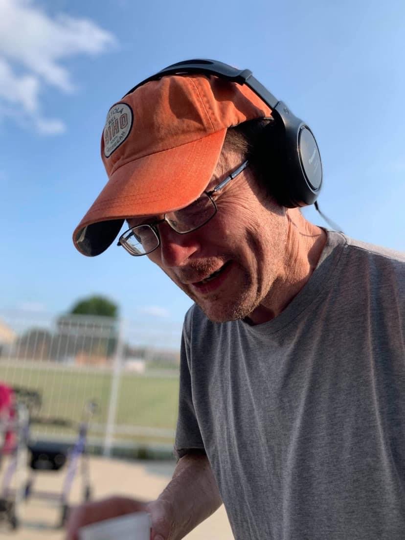 A man wearing an orange cap and headphones outdoors.