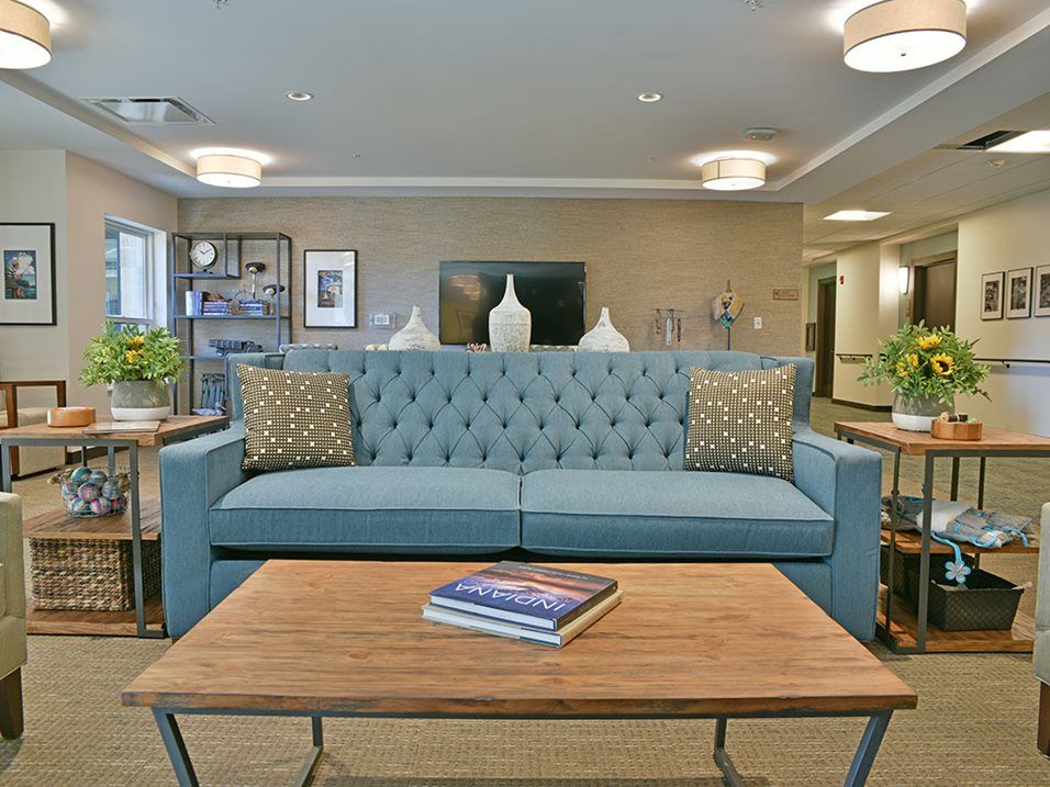A modern living room featuring a blue tufted sofa and a wooden coffee table with decorative items.