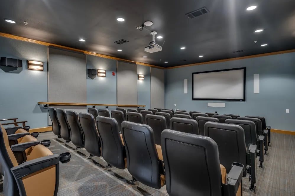 Empty theater seating with a projector and screen.