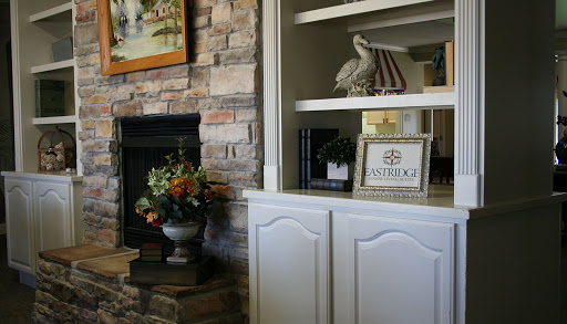 A cozy living room corner with a stone fireplace, decorative flowers, and an inviting shelf.