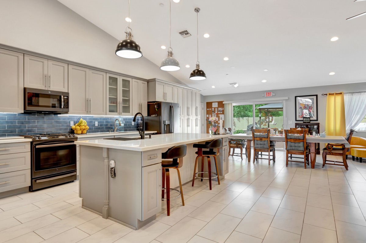 A spacious modern kitchen with an island, pendant lighting, and an open floor plan leading to a dining area.