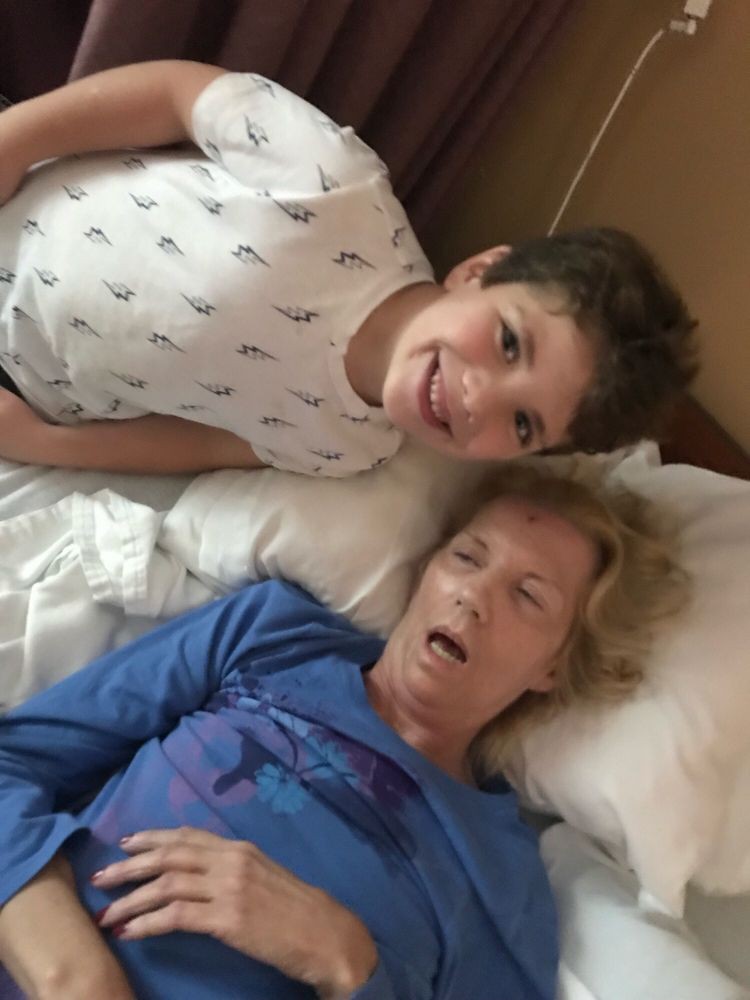 A child smiling next to an elderly person resting in bed.