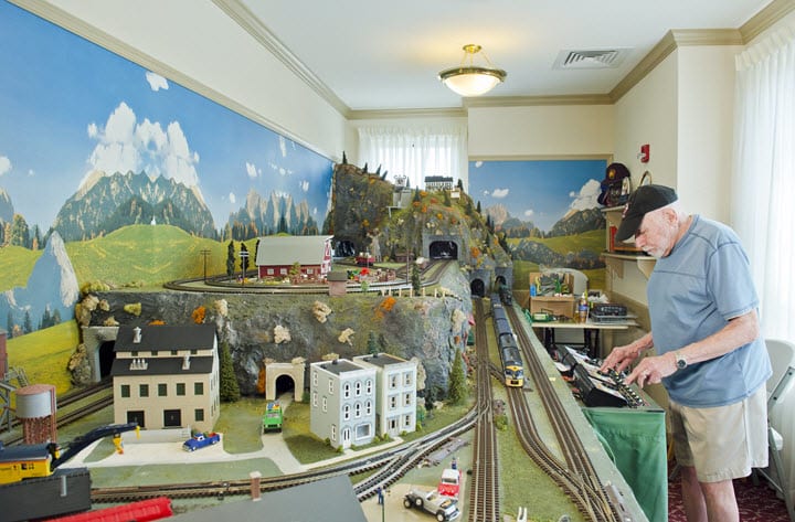 A detailed miniature train set with a scenic landscape displayed in an indoor setting.