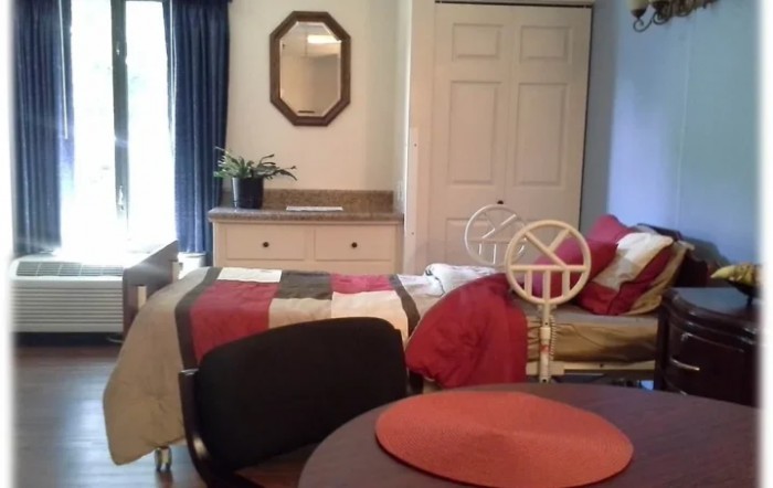 A cozy bedroom with a neatly made bed, dresser, mirror, and decor.
